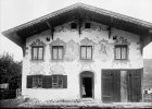 Lüftlmalerei mit Maria und Josef sowie scheinarchitektonische Fenster- und Türrahmungen aus der zweiten Hälfte des 18. Jahrhunderts auf der Putzfassade eines Wohnhauses mit Flachsatteldach in Füssen im Landkreis Ostallgäu um 1900.