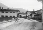 Junge mit Bierkrug und zwei Mädchen im Sonntagsgewand auf der "Alten Dorfstraße" in Marquartstein im Landkreis Traunstein um 1910.